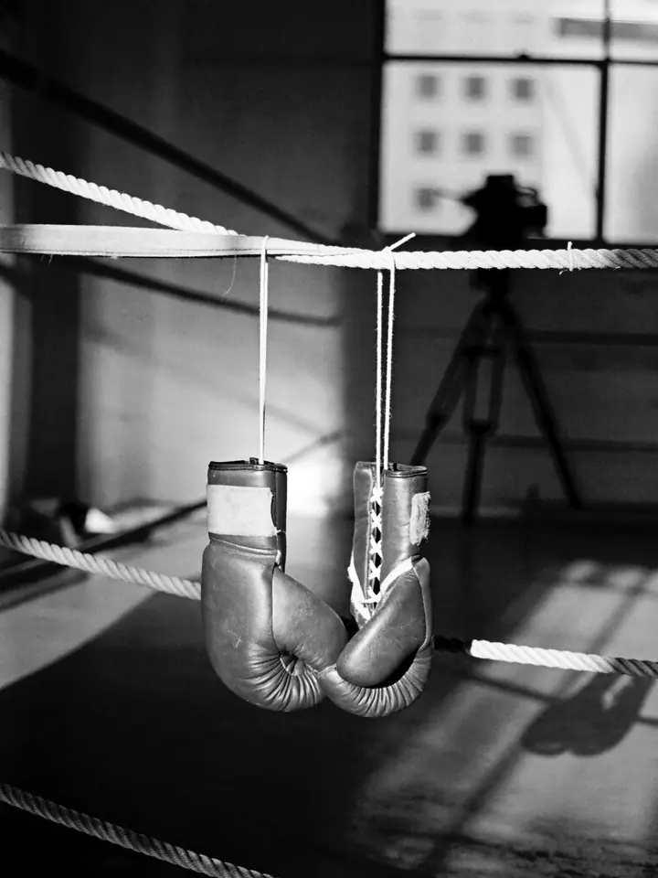 A pair of boxing gloves hanging from the ring ropes.