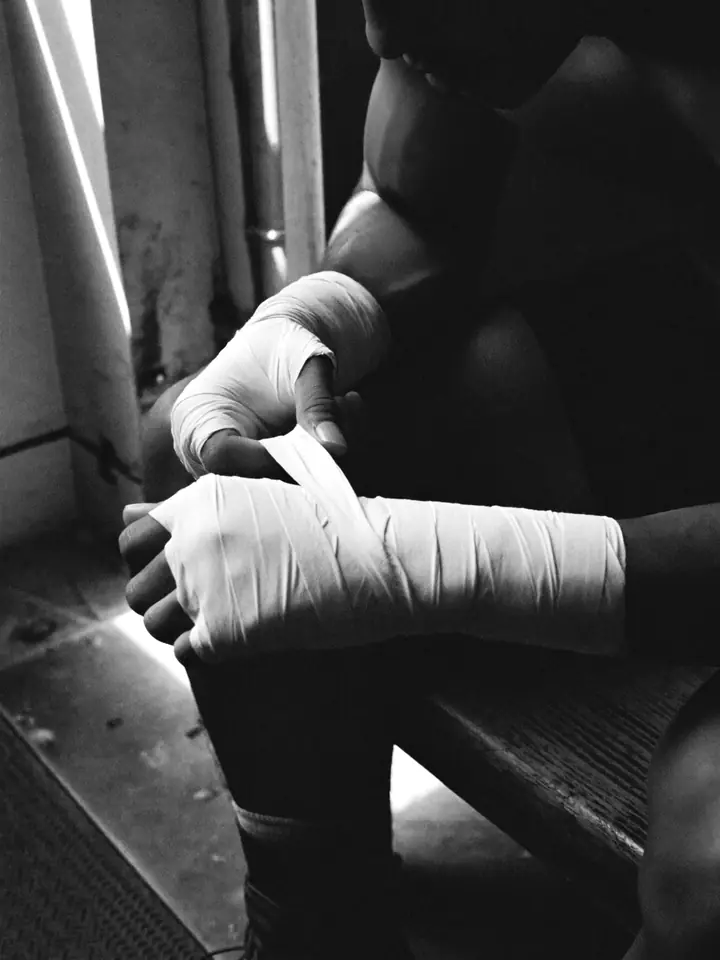 A fighter wrapping his hands on a bench before training.